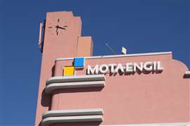 A pink building bearing Mota-Engil's logo against a blue sky