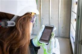 construction worker looks at plans on her phone